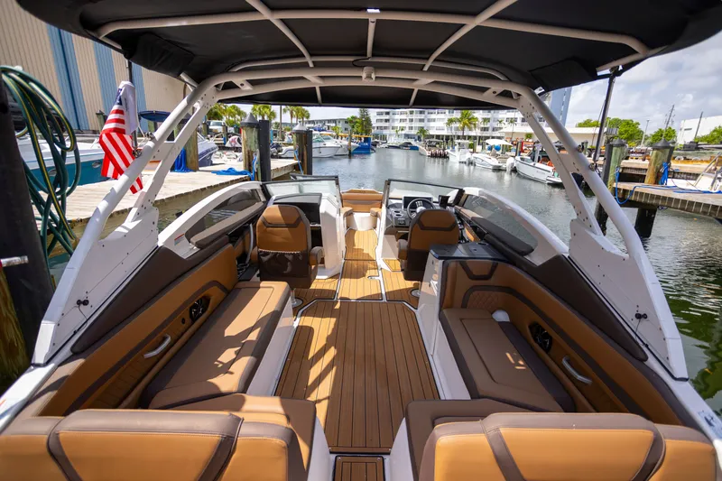 Slide: The Image of 2024 Yamaha Boats 275SE interior with luxurious seating at a marina dock. - 16