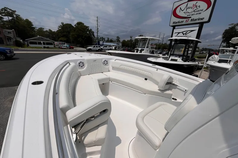Slide: The Image of 2027 Tidewater 232 CC Adventure boat interior with white seating at a marine dealership. - 11