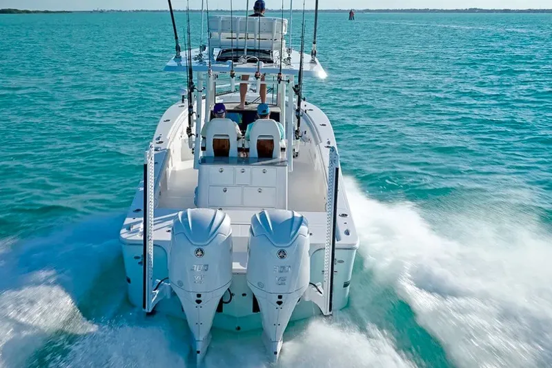 Slide: The Image of 2027 Regulator 30XO boat cruising on clear blue water, rear view with dual engines. - 3