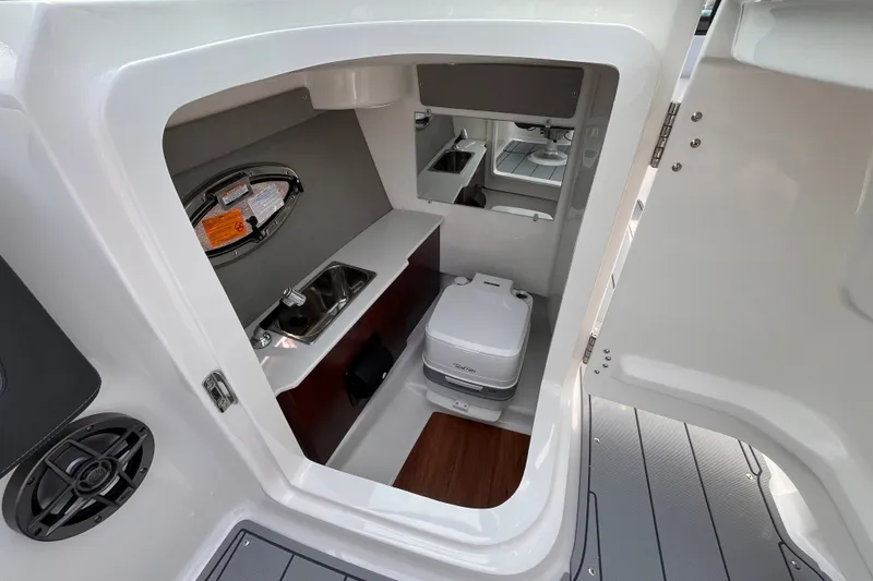 Slide: The Image of The image shows the interior of a 2025 Chaparral 250 OSX with a small toilet and sink. - 13