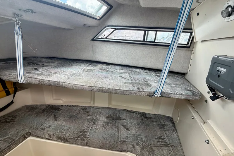 Slide: The Image of 1993 Grady-White Dolphin 250 cabin interior with cushioned seating and windows. - 10