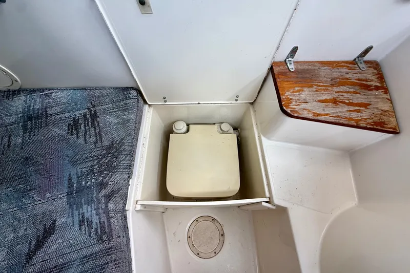 Slide: The Image of 1993 Grady-White Dolphin 250 boat interior with portable toilet and wooden seat. - 7