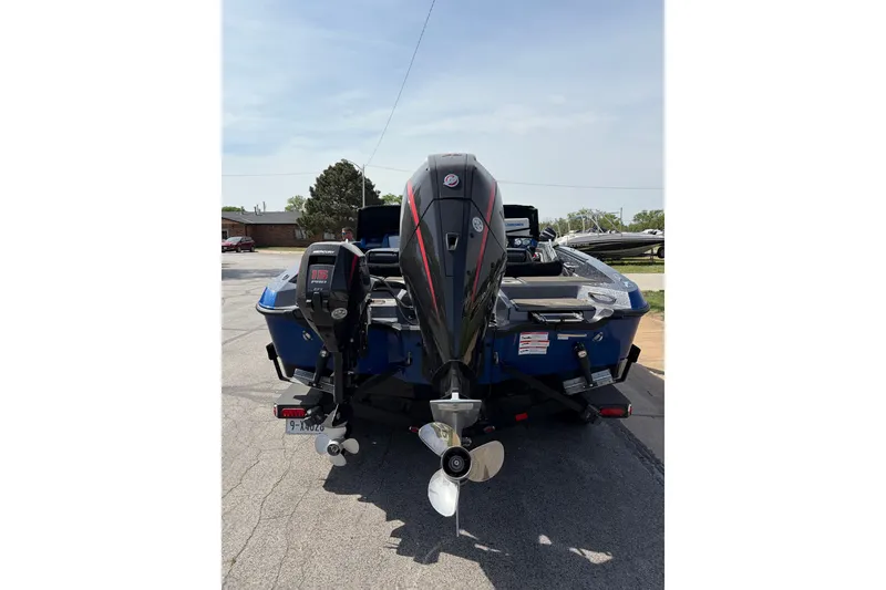 Slide: The Image of 2024 Lund 202 Pro-V GL boat, rear view with motor, parked on a trailer. - 4