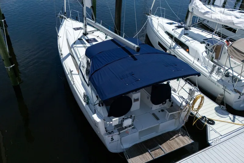 Slide: The Image of 2024 Beneteau Oceanis 34.1 sailboat docked, featuring a blue canopy and sleek design. - 51