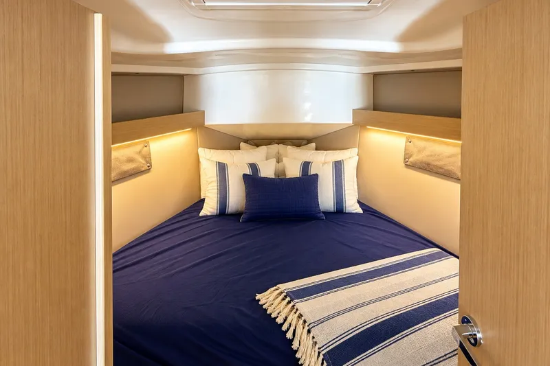 Slide: The Image of Cozy cabin interior of 2024 Beneteau Oceanis 34.1 with blue bedding and striped throw. - 26