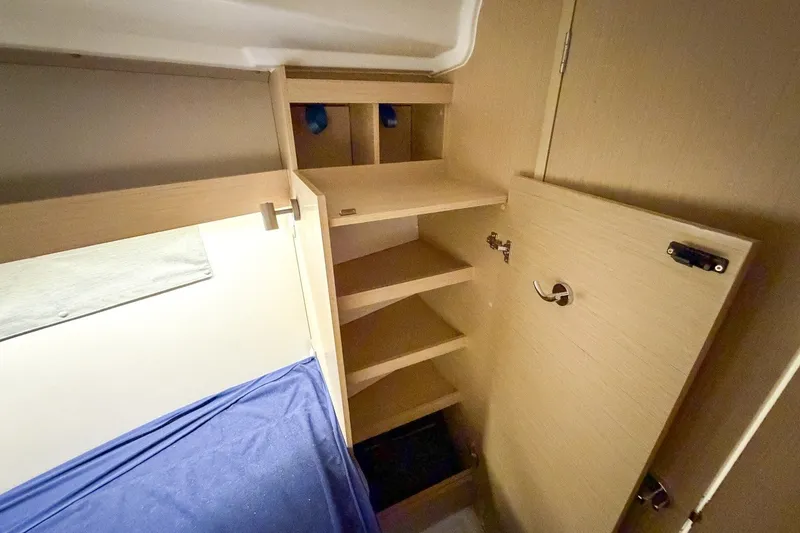 Slide: The Image of Interior cabin storage of 2024 Beneteau Oceanis 34.1 yacht with wooden shelves and blue bedding. - 25