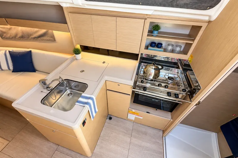 Slide: The Image of 2024 Beneteau Oceanis 34.1 yacht interior kitchen with sink, stove, and seating area. - 4