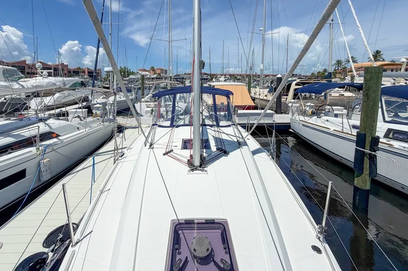 Slide: The Image of 2024 Beneteau Oceanis 34.1 sailboat docked at a marina under a clear blue sky. - 46