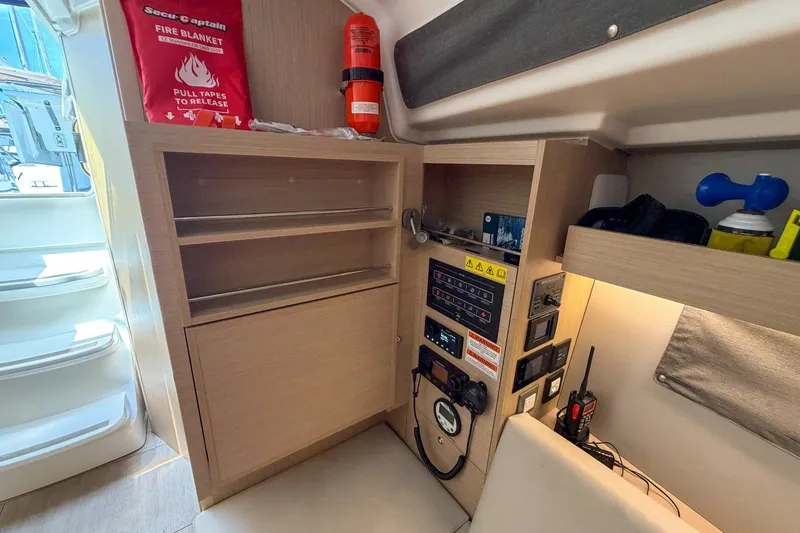 Slide: The Image of 2024 Beneteau Oceanis 34.1 interior with control panel, fire blanket, and storage shelves. - 19