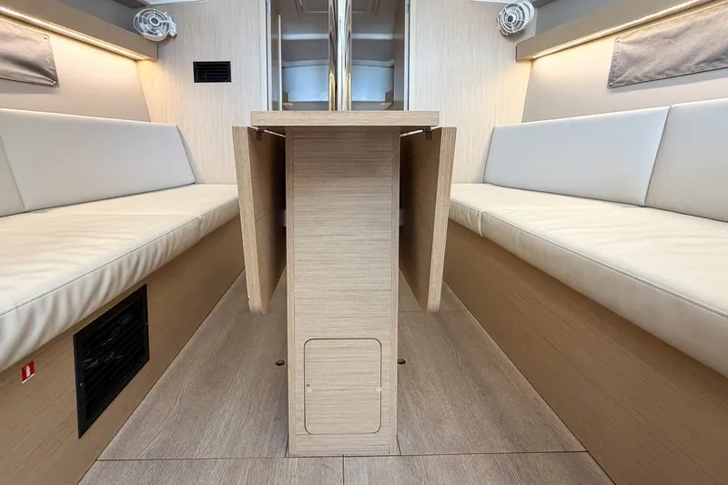 Slide: The Image of 2024 Beneteau Oceanis 34.1 interior with light wood finish and cushioned seating. - 17