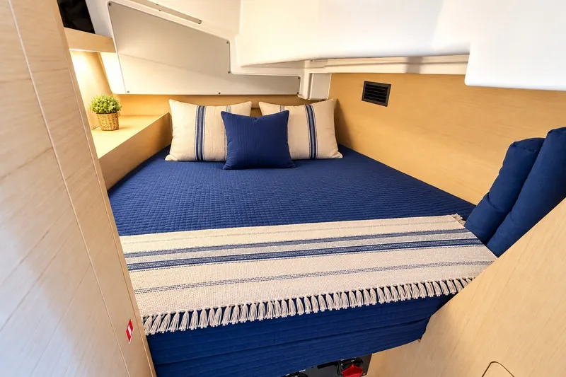 Slide: The Image of Cozy cabin interior of 2024 Beneteau Oceanis 34.1 with blue bedding and decorative pillows. - 8