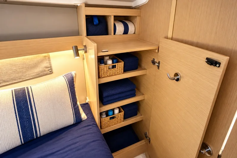 Slide: The Image of 2024 Beneteau Oceanis 34.1 cabin storage with neatly organized shelves and bedding. - 28