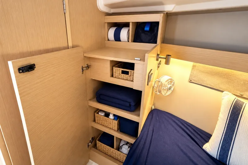 Slide: The Image of 2024 Beneteau Oceanis 34.1 cabin interior with wooden storage shelves and cozy bedding. - 27