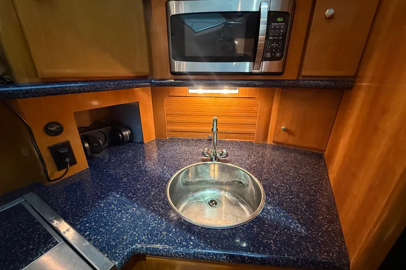 Slide: The Image of 2002 Carver 404 Cockpit Motor Yacht kitchen with sink, microwave, and blue countertop. - 46