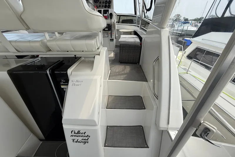 Slide: The Image of 2002 Carver 404 Cockpit Motor Yacht interior with white seating and "Collect moments not things" sign. - 20