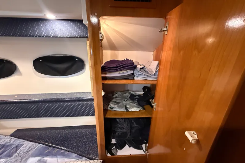 Slide: The Image of Wooden closet with folded clothes inside a 2002 Carver 404 Cockpit Motor Yacht cabin. - 62