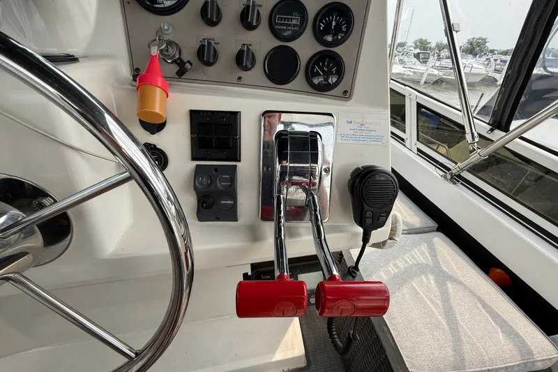 Slide: The Image of Control panel of a 2002 Carver 404 Cockpit Motor Yacht with steering wheel and throttle levers. - 25