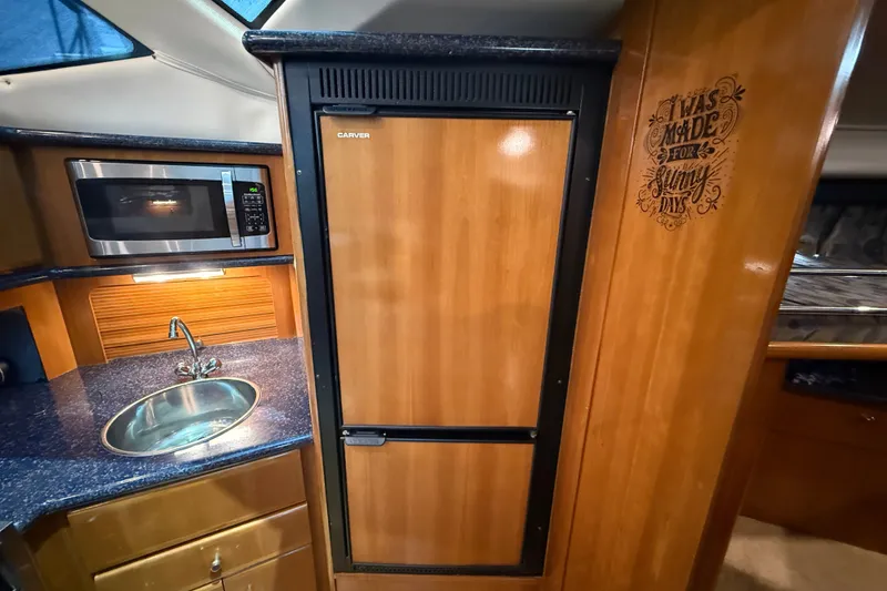 Slide: The Image of 2002 Carver 404 Cockpit Motor Yacht kitchen with microwave, sink, and wooden cabinetry. - 47