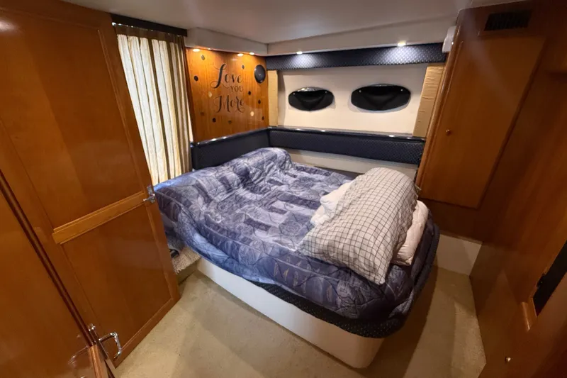 Slide: The Image of Interior of 2002 Carver 404 Cockpit Motor Yacht bedroom with cozy bedding and wood paneling. - 59