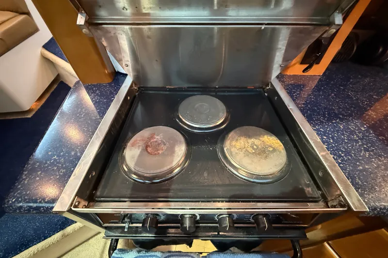 Slide: The Image of Stove inside 2002 Carver 404 Cockpit Motor Yacht, featuring three burners and stainless steel finish. - 48