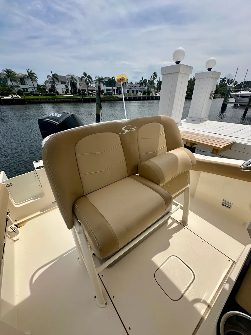 Slide: The Image of A 2019 Scout 235 XSF with beige seats, docked by the water, with palm trees in the background. - 2