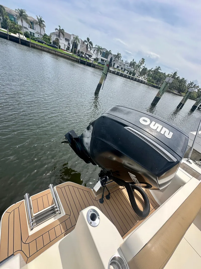 Slide: The Image of A 2019 Scout 235 XSF boat with an outboard motor, docked by a calm waterway. - 7