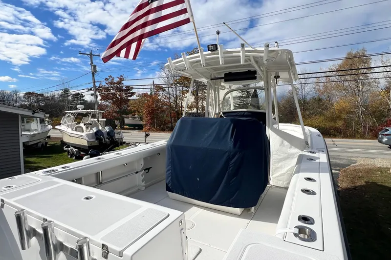 Slide: The Image of 2008 Edgewater 318CC boat with American flag, parked outdoors under a clear sky. - 19