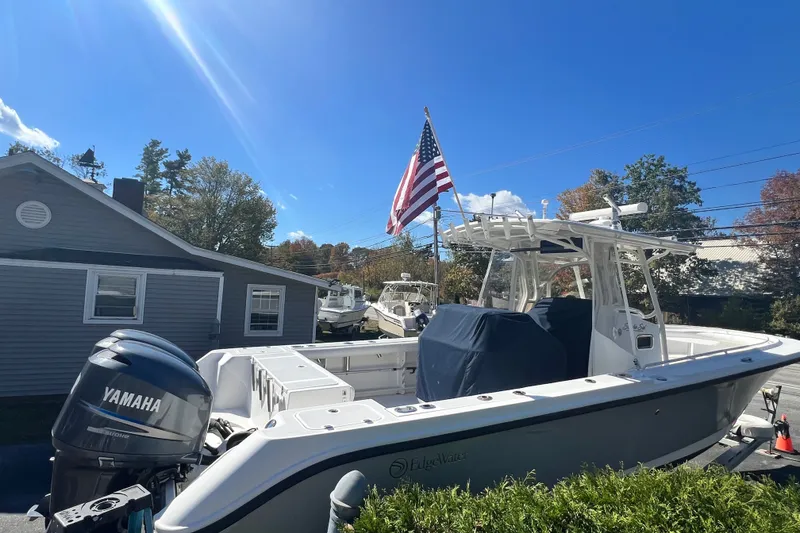 Slide: The Image of 2008 Edgewater 318CC boat with Yamaha engine, American flag, parked near a house. - 3