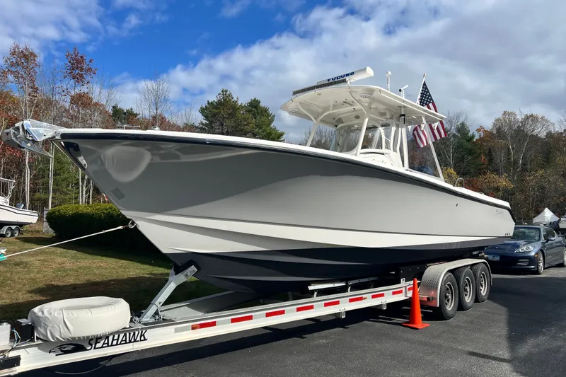 Slide: The Image of 2008 Edgewater 318CC boat on trailer, parked outdoors under a partly cloudy sky. - 16