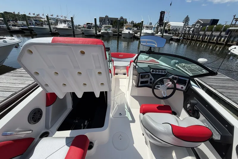 Slide: The Image of 2017 MasterCraft NXT20 Global Edition boat interior with red and white seating at a marina. - 10