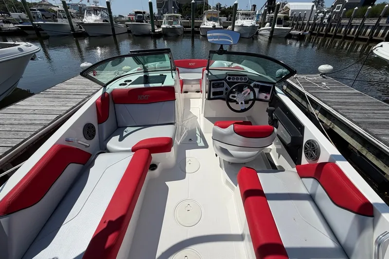 Slide: The Image of 2017 MasterCraft NXT20 Global Edition boat interior with red and white seating at a marina. - 9