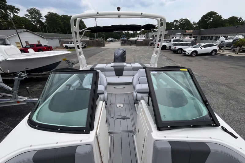Slide: The Image of 2027 Chaparral 21 SSi OB boat with sleek interior and windshield, parked in a marina. - 16