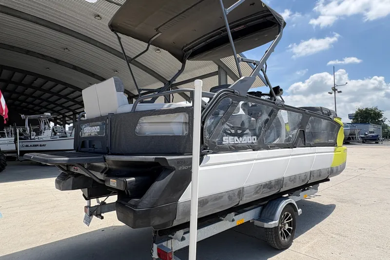 Slide: The Image of 2023 Seadoo Switch 21 pontoon boat on trailer, parked outdoors under a metal roof. - 4