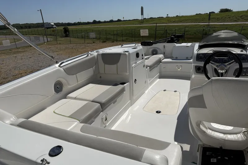 Slide: The Image of 2021 Tahoe 2150 boat interior with white seating and steering wheel, parked outdoors. - 4