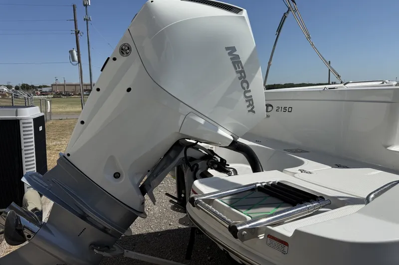 Slide: The Image of 2021 Tahoe 2150 boat with Mercury outboard motor, docked outdoors. - 2
