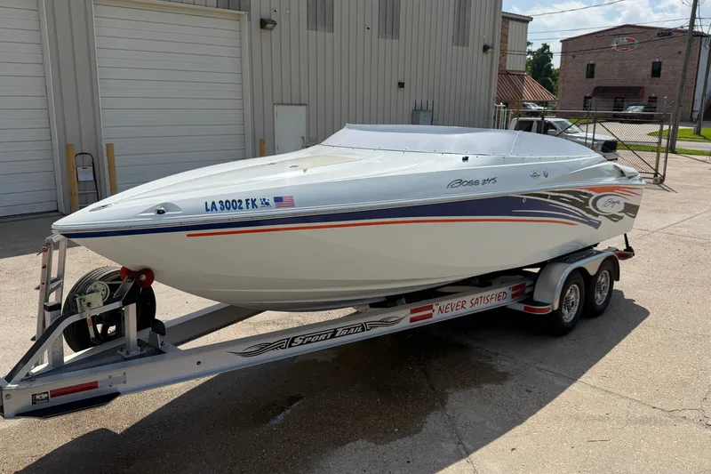 Slide: The Image of 2004 Baja 245 Performance boat on trailer, parked outside industrial building. - 3