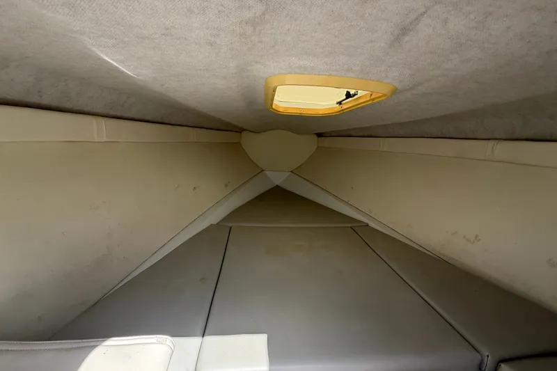 Slide: The Image of Interior cabin of a 2004 Baja 245 Performance boat, featuring beige upholstery. - 13