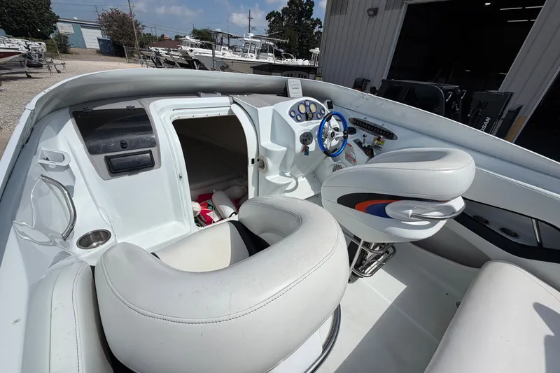 Slide: The Image of 2004 Baja 245 Performance boat interior with white seating and blue steering wheel. - 19