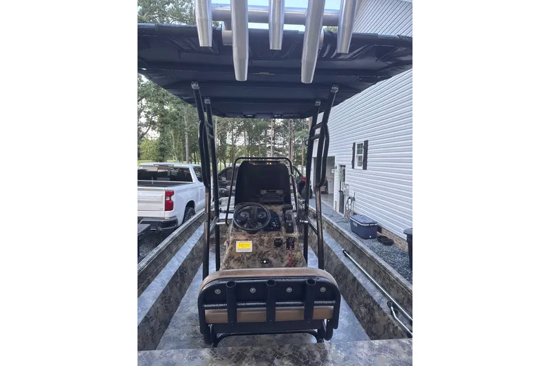 Slide: The Image of 2023 Excel 2172 Stalker CC boat with camouflage design, parked outdoors near vehicles. - 3