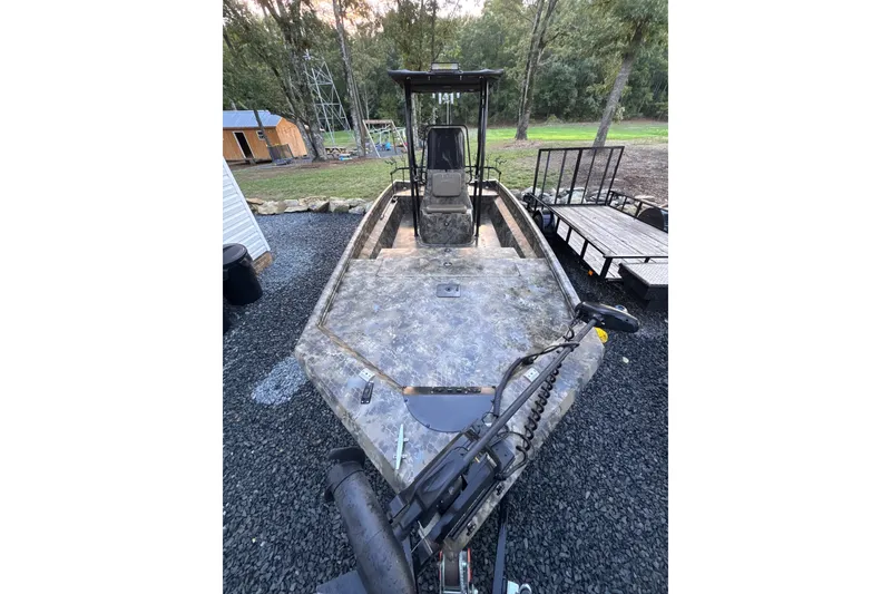 Slide: The Image of 2023 Excel 2172 Stalker CC boat with camouflage design, parked outdoors on gravel. - 4