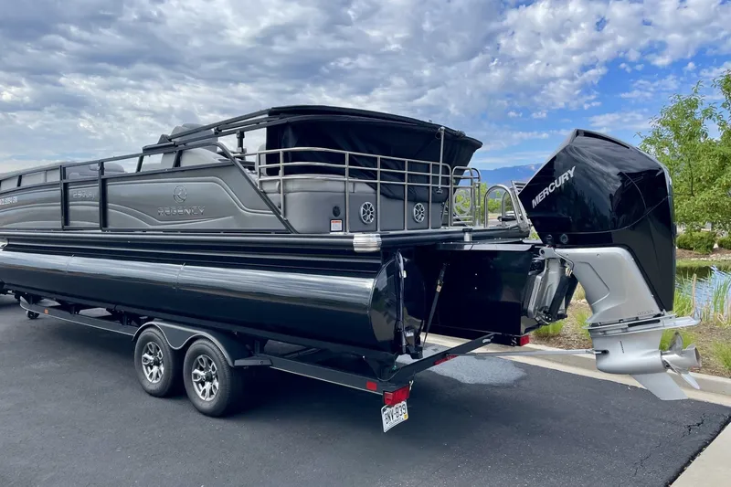 Slide: The Image of 2023 Regency 250LE pontoon boat with Mercury outboard engine on trailer. - 2