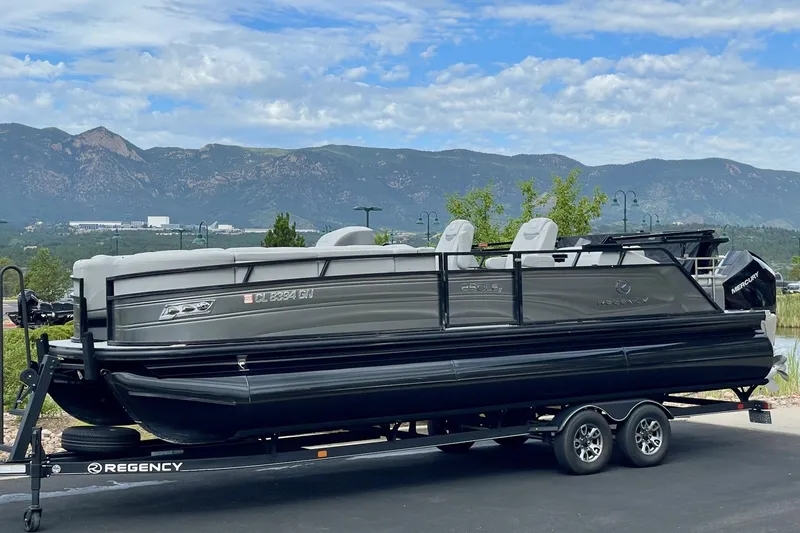 Slide: The Image of 2023 Regency 250LE pontoon boat on trailer with scenic mountain backdrop. - 5