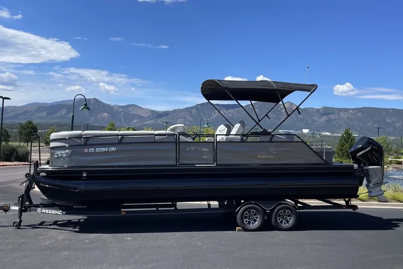 The Image of 2023 Regency 250LE pontoon boat on trailer with scenic mountain backdrop. - 0