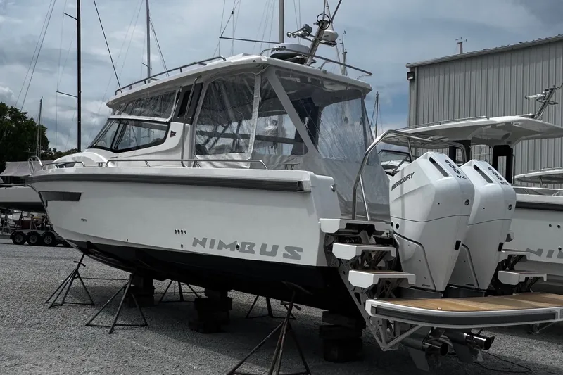 Slide: The Image of Nimbus Weekender 11 boat, 2026 model, with dual Mercury engines, displayed on stands. - 0