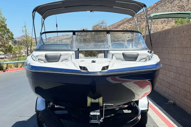 Slide: The Image of 2017 Yamaha Boats 212 Limited on trailer, parked outdoors with scenic background. - 2