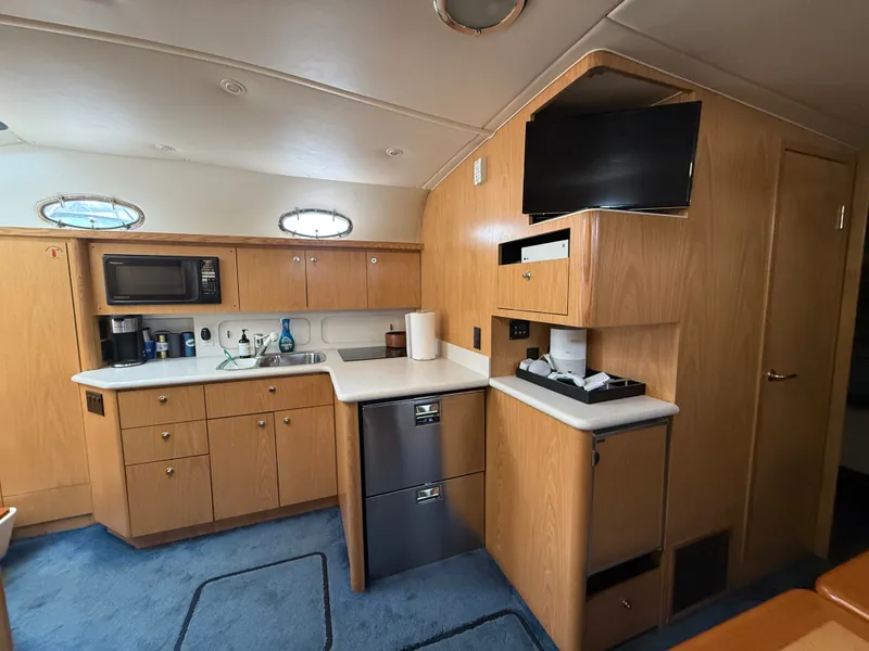 Slide: The Image of The interior of a 1999 Tiara Yachts 4000 Express features a well-equipped kitchen with wooden cabinets. - 21