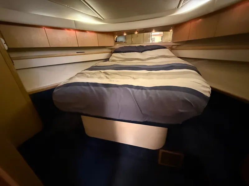 Slide: The Image of The cabin of the 1999 Tiara Yachts 4000 Express features a cozy bed with striped bedding. - 32