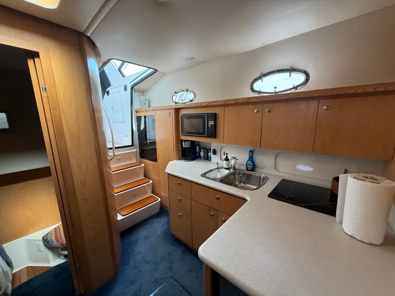 Slide: The Image of The interior of a 1999 Tiara Yachts 4000 Express features a well-equipped galley with wooden cabinets. - 26