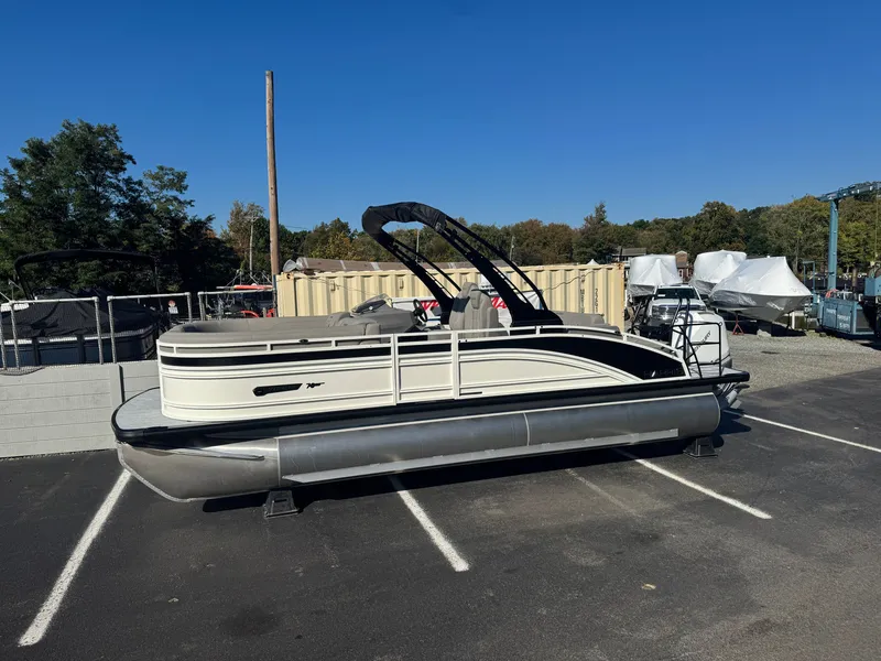 Slide: The Image of A 2027 Harris 230SOL pontoon boat is parked in a lot. It features a black canopy. - 4