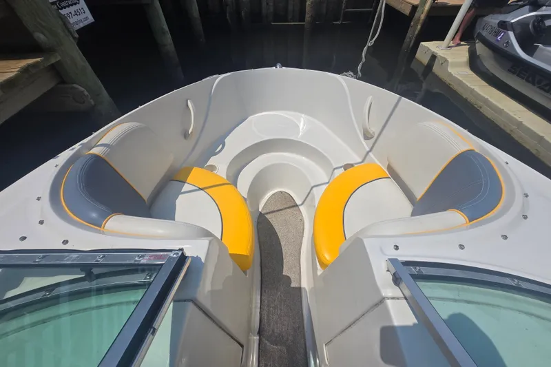 Slide: The Image of 2007 Sea Ray 185 Sport boat interior with yellow and gray seating, docked at marina. - 2